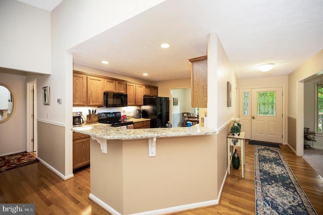 106 Tallwood Trl, Locust Grove, VA 22508 - kitchen with black appliances, wood finished floors, light stone countertops, a kitchen bar, and brown cabinetry
