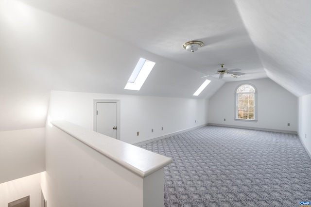 additional living space with baseboards, carpet floors, a ceiling fan, and vaulted ceiling with skylight