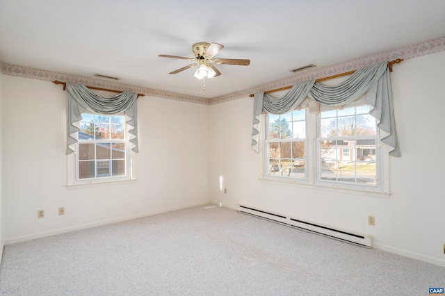 spare room featuring carpet, visible vents, a ceiling fan, and a baseboard heating unit