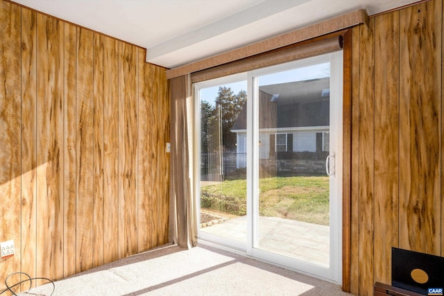 doorway featuring carpet and wood walls