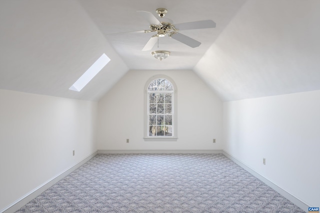 additional living space with baseboards, lofted ceiling with skylight, carpet flooring, and ceiling fan