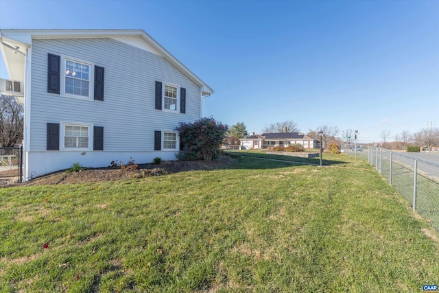 view of side of home featuring fence and a lawn