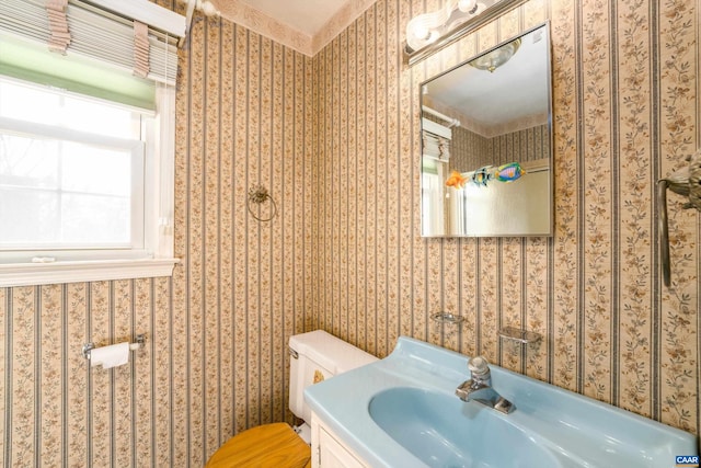bathroom with a sink, toilet, and wallpapered walls