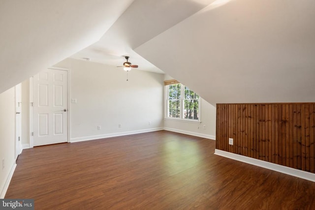 bonus room featuring dark wood-style floors, vaulted ceiling, a ceiling fan, and baseboards