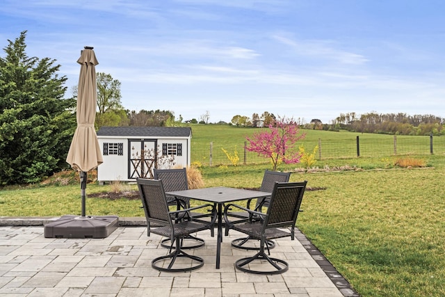 141 Tomasville Dr, Waynesboro, VA 22980 - view of patio / terrace featuring a rural view, a storage unit, fence, outdoor dining area, and an outbuilding