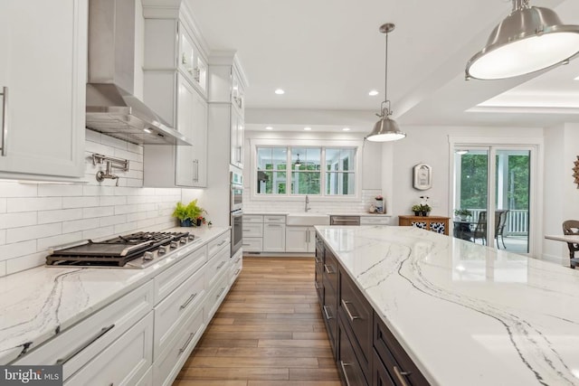 11206 Preswick Ln, Spotsylvania, VA 22551 - kitchen featuring wall chimney exhaust hood, a sink, wood finished floors, white cabinets, and recessed lighting