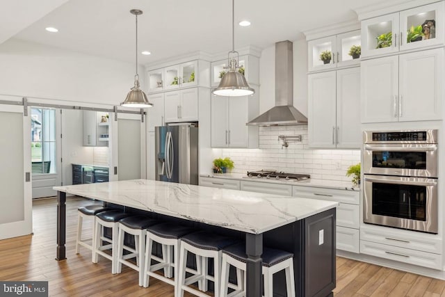 11206 Preswick Ln, Spotsylvania, VA 22551 - kitchen featuring stainless steel appliances, wall chimney range hood, a center island, tasteful backsplash, and white cabinetry