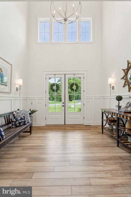 11206 Preswick Ln, Spotsylvania, VA 22551 - foyer entrance with a towering ceiling, a chandelier, a decorative wall, a wainscoted wall, and light wood-type flooring