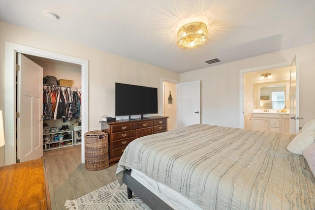 bedroom featuring a walk in closet, connected bathroom, light hardwood / wood-style floors, and a closet