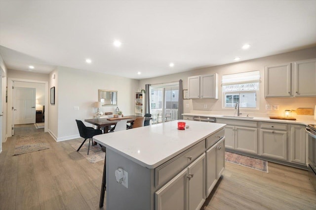 kitchen with gray cabinetry, sink, a center island, and light wood-type flooring