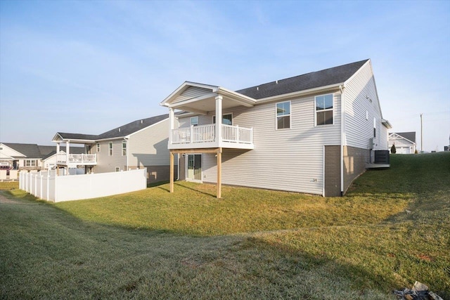 rear view of property with a balcony and a lawn