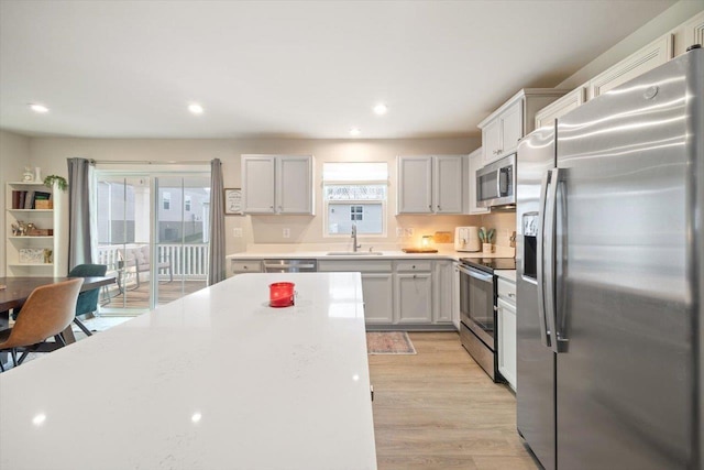 kitchen with white cabinetry, sink, light wood-type flooring, and appliances with stainless steel finishes