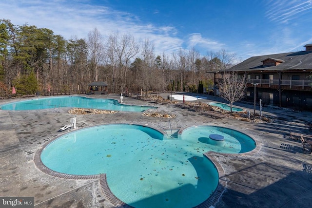 view of pool with a hot tub and a patio