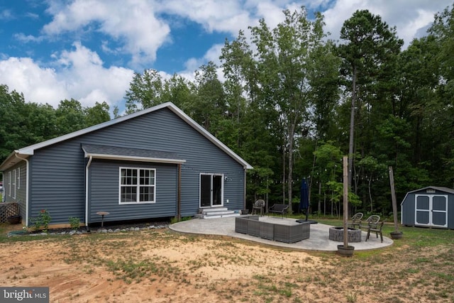 back of property featuring a storage shed, a lawn, a patio area, and an outdoor fire pit