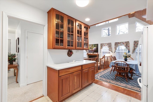 130 Rainier Rd, Mcgaheysville, VA 22840 - kitchen with freestanding refrigerator, glass insert cabinets, brown cabinetry, light countertops, and a high ceiling