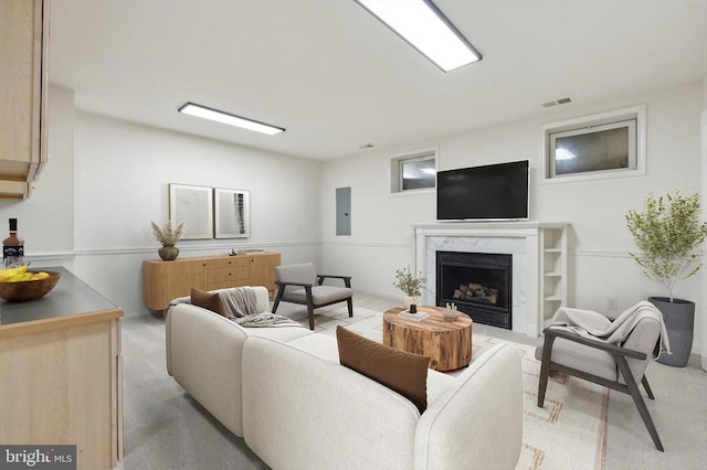 living room featuring a fireplace, electric panel, and light colored carpet