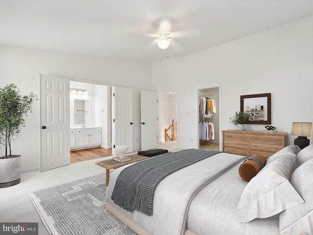 bedroom featuring light colored carpet, ensuite bath, lofted ceiling, and a walk in closet