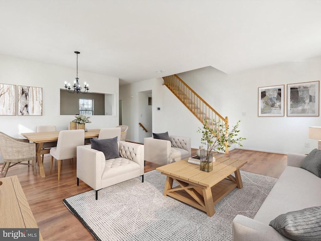 living room featuring a chandelier, light wood-type flooring, and stairway