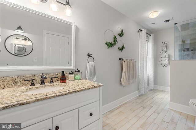 bathroom with vanity, hardwood / wood-style floors, toilet, and walk in shower