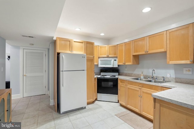 kitchen featuring light brown cabinetry, sink, white appliances, and light tile patterned flooring