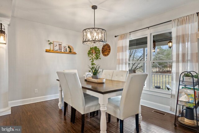 dining space featuring dark hardwood / wood-style floors and an inviting chandelier