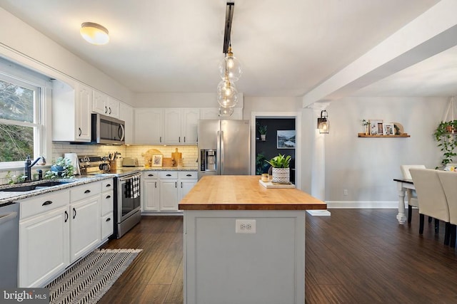 kitchen featuring butcher block counters, sink, appliances with stainless steel finishes, a kitchen island, and white cabinets