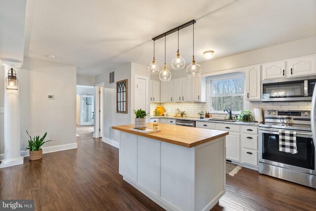 kitchen with butcher block counters, sink, white cabinets, a center island, and stainless steel appliances