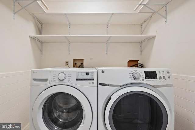 washroom with washing machine and clothes dryer and tile walls