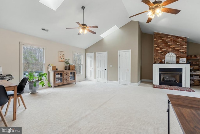 living room with a skylight, light colored carpet, high vaulted ceiling, ceiling fan, and a fireplace