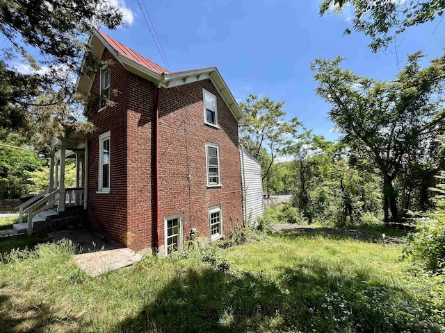 view of side of home with brick siding, metal roof, and a standing seam roof