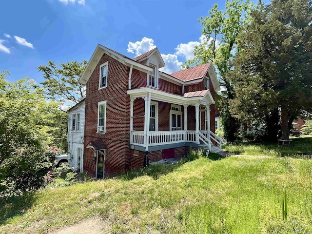 view of home's exterior featuring covered porch, brick siding, and metal roof