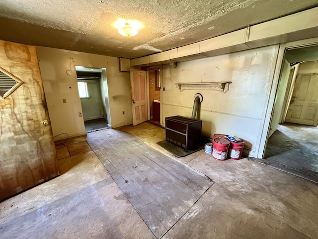 basement with a wood stove and a textured ceiling