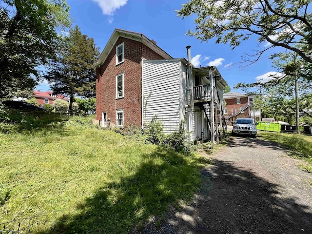 view of side of property with brick siding, stairway, and driveway