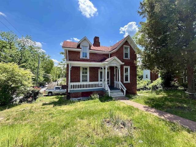 view of front facade with covered porch, brick siding, and a chimney