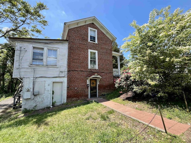 rear view of property featuring a lawn and brick siding