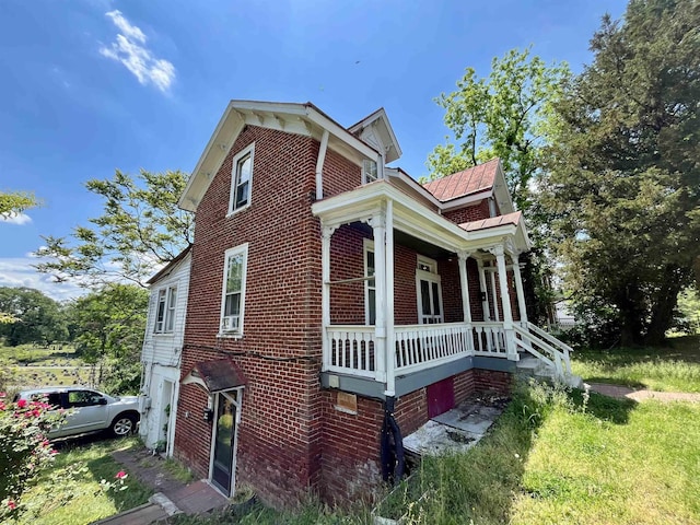 view of side of home with brick siding and a porch
