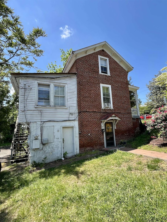 view of front of house with stairs, a front yard, and brick siding