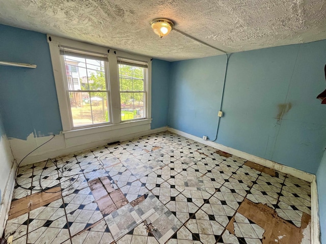 spare room with a textured ceiling and baseboards