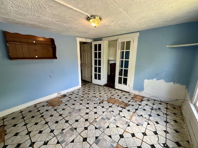 spare room with french doors, baseboards, and a textured ceiling