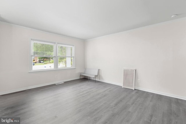 unfurnished room featuring baseboards, visible vents, crown molding, and wood finished floors