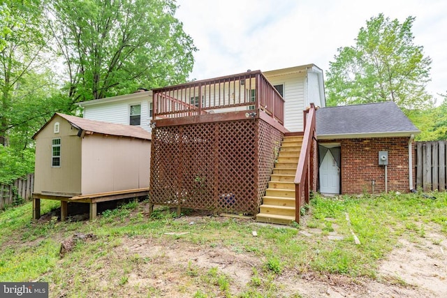 rear view of property with a wooden deck, fence, an outdoor structure, a storage unit, and stairs
