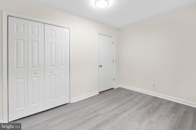 unfurnished bedroom with wood finished floors, a closet, and baseboards