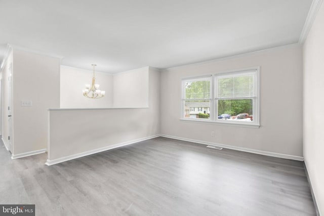 unfurnished room featuring crown molding, wood finished floors, baseboards, and an inviting chandelier