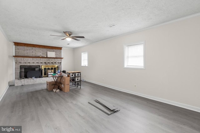 living area with wood finished floors, a brick fireplace, ceiling fan, baseboards, and ornamental molding