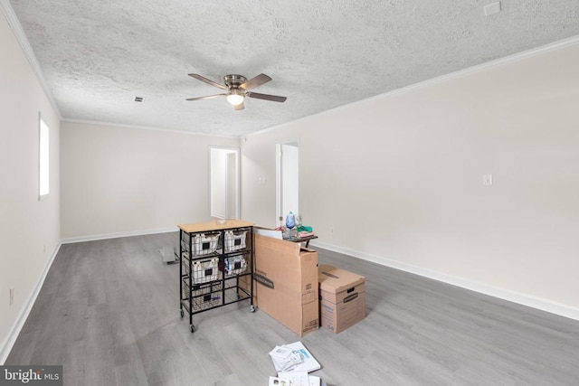 unfurnished room featuring wood finished floors, ceiling fan, a textured ceiling, ornamental molding, and baseboards