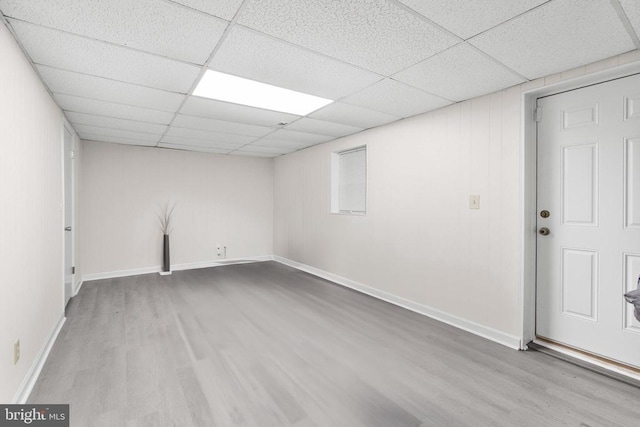 below grade area featuring wood finished floors, a paneled ceiling, and baseboards