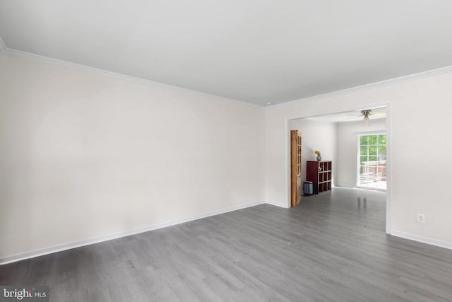 empty room featuring dark wood-style floors, ornamental molding, baseboards, and a ceiling fan