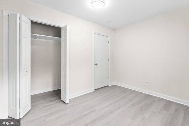 unfurnished bedroom with wood finished floors, a closet, and baseboards