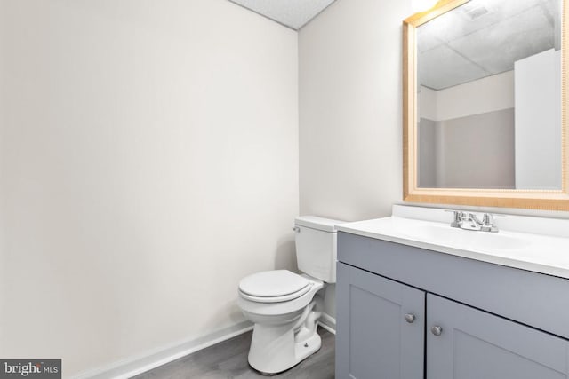 bathroom featuring baseboards, vanity, toilet, and wood finished floors