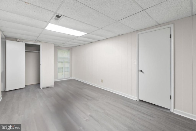 unfurnished bedroom with a paneled ceiling, wood finished floors, and a closet